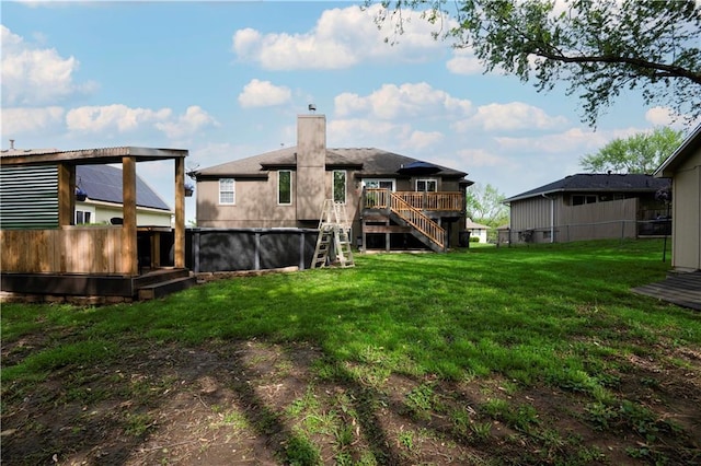rear view of property featuring a chimney, a lawn, a deck, fence, and stairs
