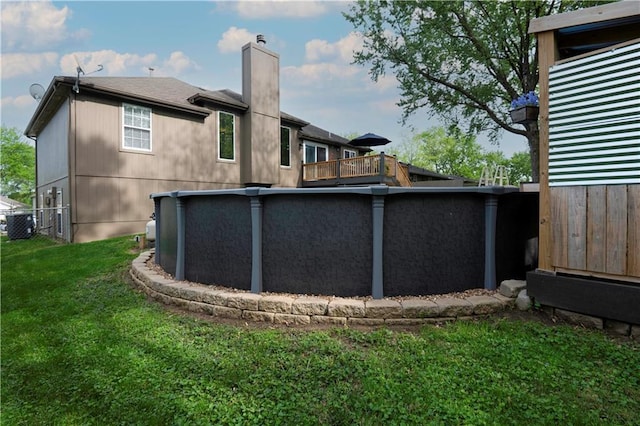 back of property with a lawn, a pool, a chimney, and central air condition unit