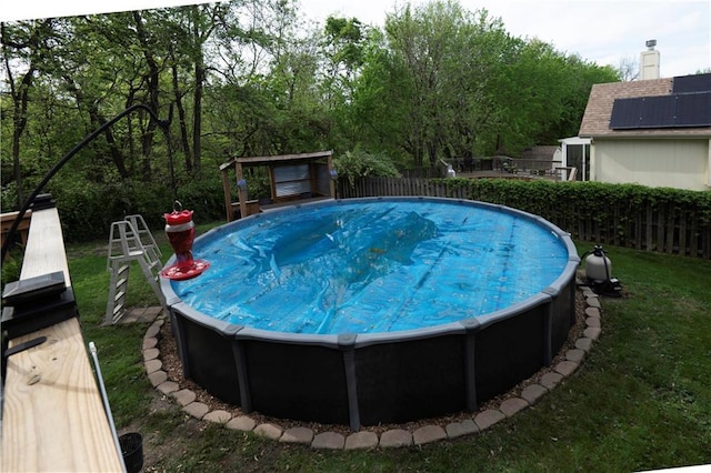 view of swimming pool with a jacuzzi, fence, and a yard