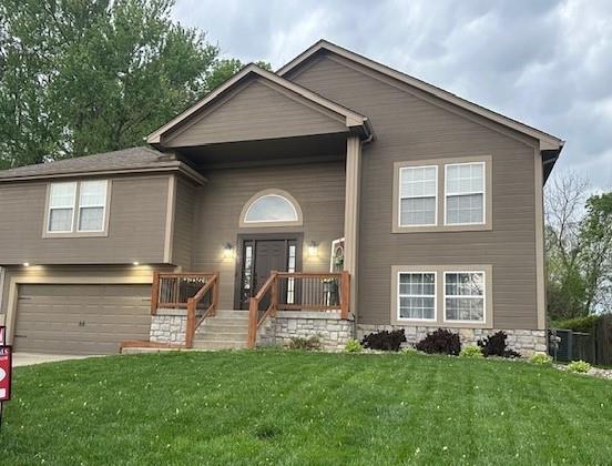 split foyer home featuring a garage, driveway, and a front lawn