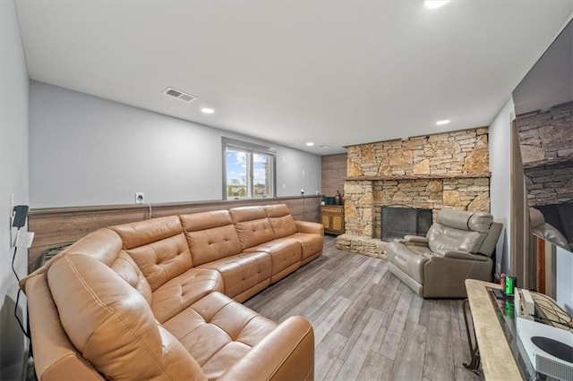 living area featuring visible vents, a stone fireplace, and light wood-style floors