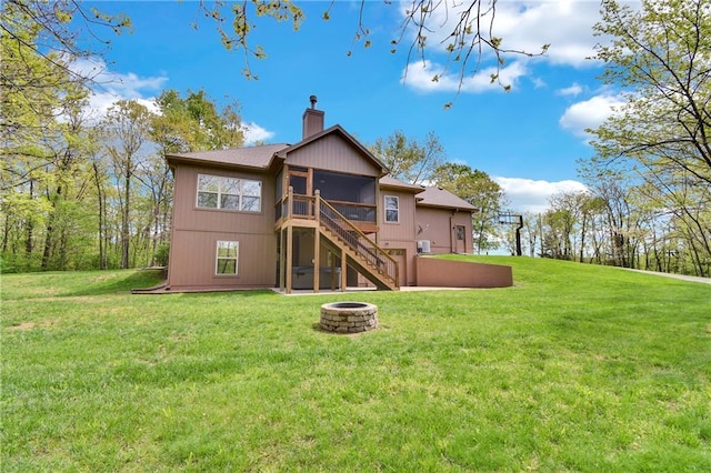 rear view of house featuring stairs, a sunroom, a chimney, a yard, and a fire pit