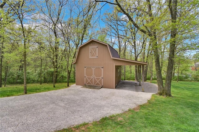 view of barn featuring a lawn, a carport, and driveway