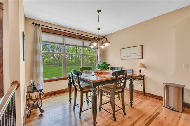dining space with baseboards, a chandelier, and light wood-style flooring