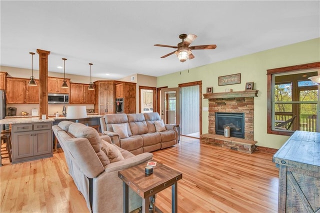 living area with recessed lighting, a fireplace, a ceiling fan, and light wood finished floors