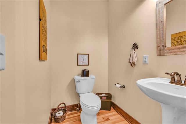 bathroom featuring a sink, baseboards, toilet, and wood finished floors