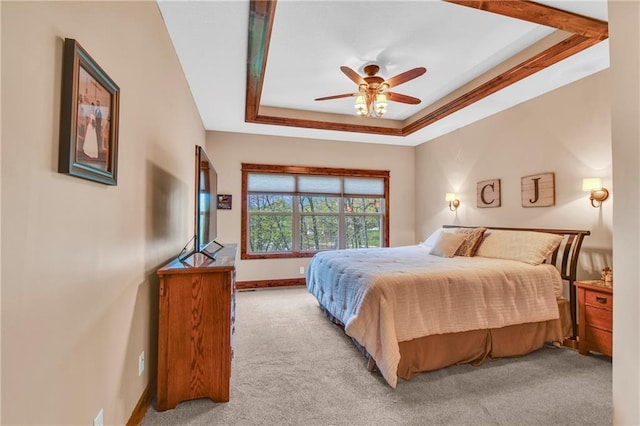carpeted bedroom featuring baseboards, a ceiling fan, and a tray ceiling