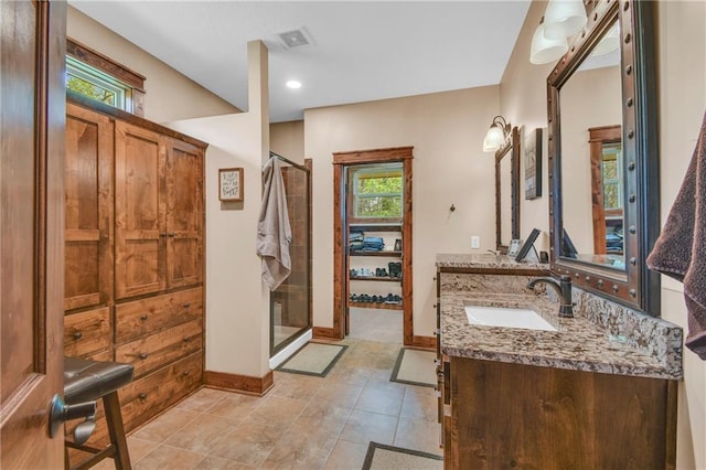 bathroom with vanity, baseboards, a shower stall, and visible vents