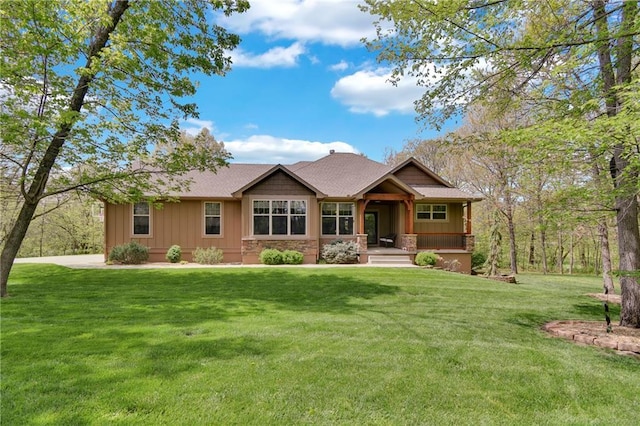 view of front of property featuring roof with shingles, covered porch, board and batten siding, and a front yard