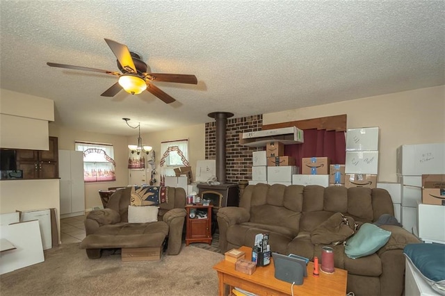 living area with a textured ceiling, a wood stove, light colored carpet, and ceiling fan with notable chandelier