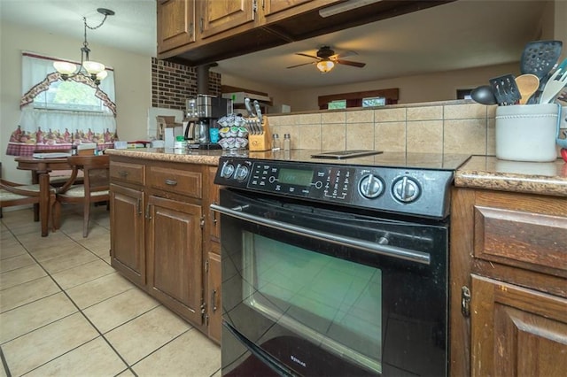 kitchen with brown cabinets, range with electric cooktop, a ceiling fan, light tile patterned floors, and hanging light fixtures