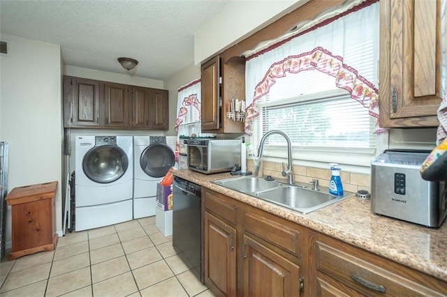 clothes washing area with laundry area, light tile patterned floors, a sink, independent washer and dryer, and a textured ceiling