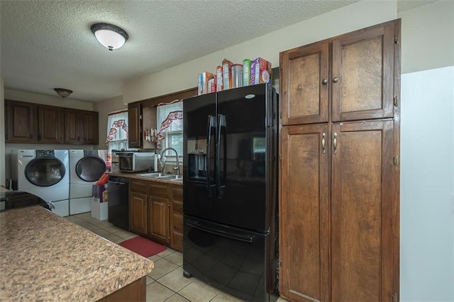 kitchen featuring a sink, a textured ceiling, independent washer and dryer, black appliances, and light tile patterned floors