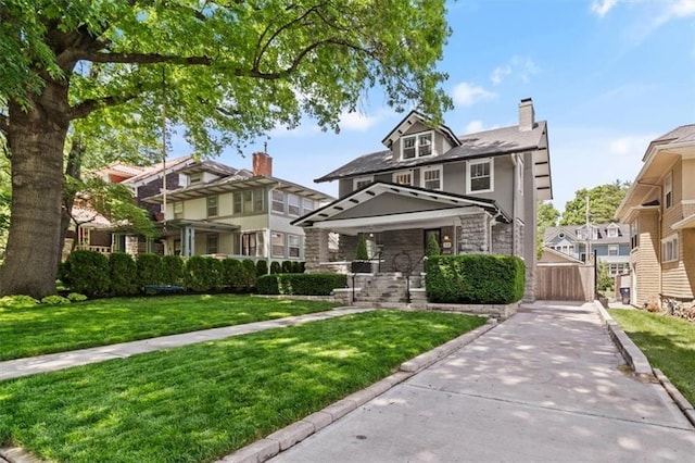 12 E 57th St, Kansas City, MO 64113 - american foursquare style home featuring a chimney, a front lawn, stone siding, a porch, and a residential view