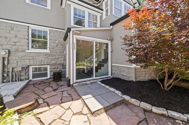 12 E 57th St, Kansas City, MO 64113 - view of exterior entry featuring stone siding, a patio area, and stucco siding