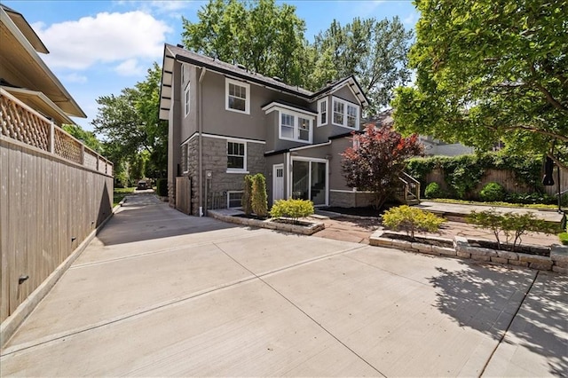 12 E 57th St, Kansas City, MO 64113 - view of front of home with stone siding, fence, and stucco siding