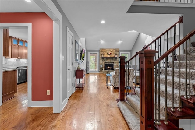 3610 NE Basswood Dr, Lees Summit, MO 64064 - entryway featuring stairway, light wood-style floors, a stone fireplace, baseboards, and lofted ceiling
