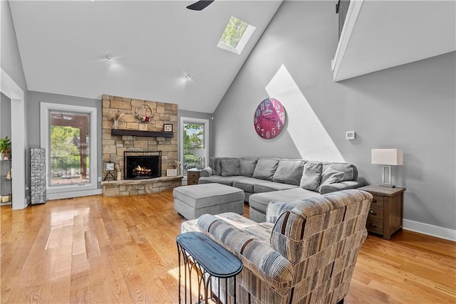 3610 NE Basswood Dr, Lees Summit, MO 64064 - living room with a skylight, high vaulted ceiling, light wood-style flooring, a fireplace, and baseboards