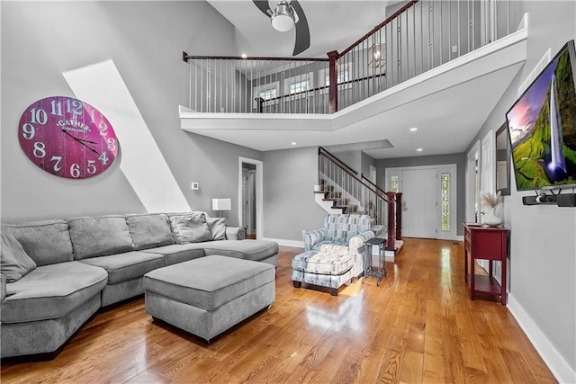 3610 NE Basswood Dr, Lees Summit, MO 64064 - living area with stairs, wood finished floors, a towering ceiling, ceiling fan, and baseboards
