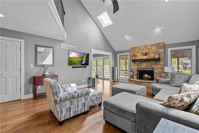 3610 NE Basswood Dr, Lees Summit, MO 64064 - living area featuring high vaulted ceiling, a skylight, baseboards, wood finished floors, and a stone fireplace
