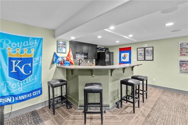 3610 NE Basswood Dr, Lees Summit, MO 64064 - indoor wet bar featuring freestanding refrigerator, recessed lighting, baseboards, and backsplash