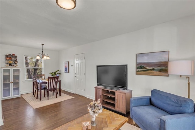 living area with baseboards, wood finished floors, and a chandelier