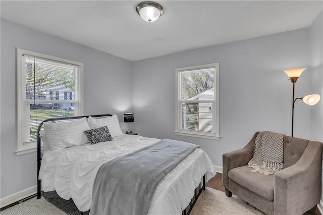 bedroom featuring baseboards, wood finished floors, and multiple windows