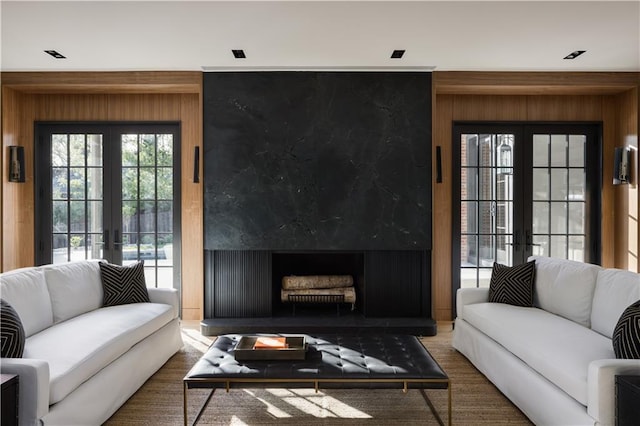 living room with a premium fireplace, french doors, and wooden walls
