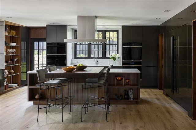 interior space with island exhaust hood, dobule oven black, modern cabinets, open shelves, and a kitchen island