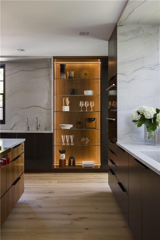 bar with light wood-type flooring and decorative backsplash
