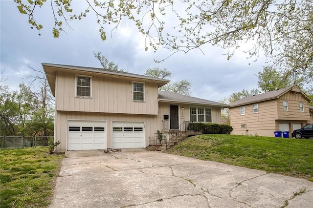 tri-level home with a garage, fence, a front yard, and driveway