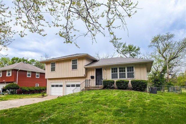 split level home with a front lawn, a garage, central AC unit, concrete driveway, and fence
