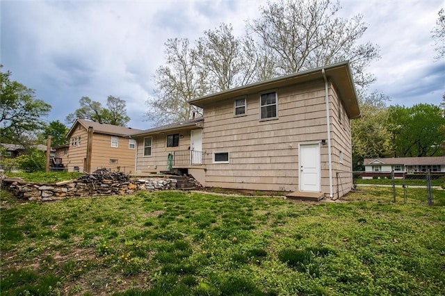 back of property featuring a lawn and fence