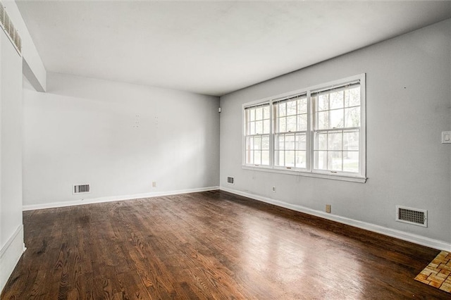 empty room with visible vents, baseboards, and dark wood-type flooring