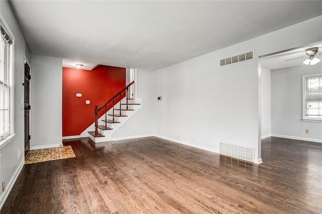 unfurnished living room featuring baseboards, visible vents, wood finished floors, and stairs