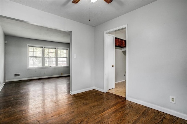 spare room featuring wood finished floors, a ceiling fan, and baseboards