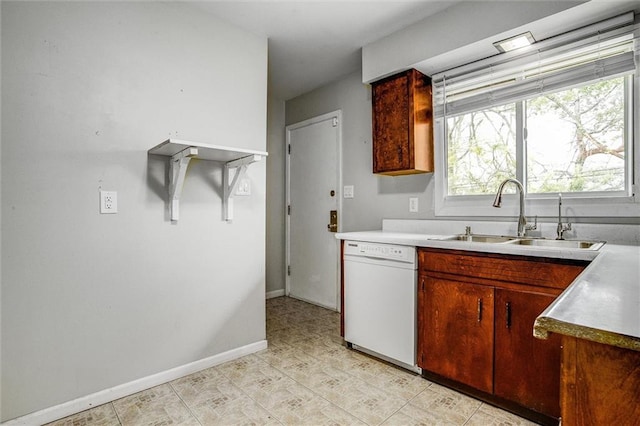 kitchen featuring baseboards, dishwasher, light countertops, and a sink