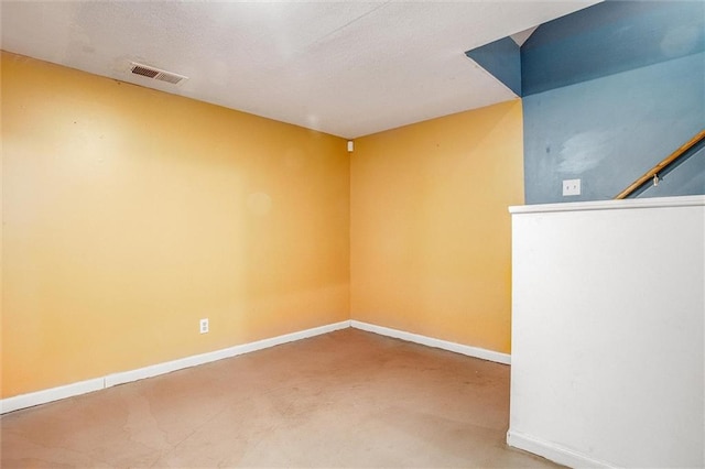 empty room featuring concrete floors, visible vents, and baseboards