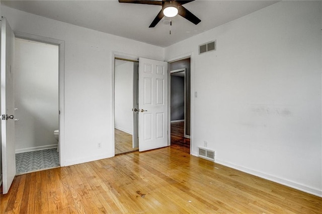 unfurnished bedroom with ensuite bathroom, visible vents, baseboards, and light wood-type flooring