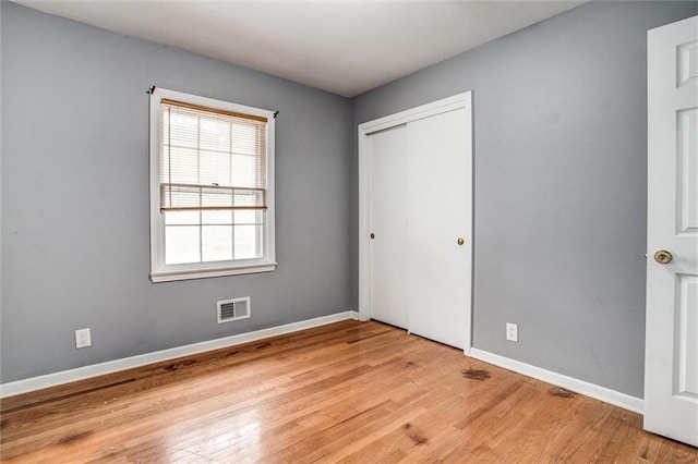 unfurnished bedroom featuring a closet, visible vents, baseboards, and light wood-type flooring