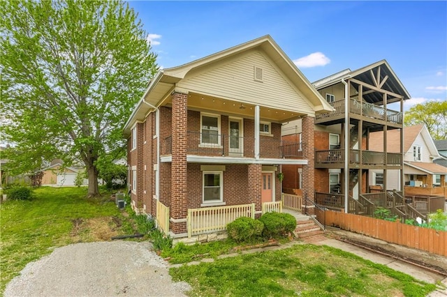 multi unit property featuring a porch, a front yard, and brick siding