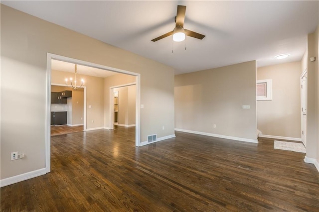 spare room featuring dark wood finished floors, visible vents, ceiling fan with notable chandelier, and baseboards