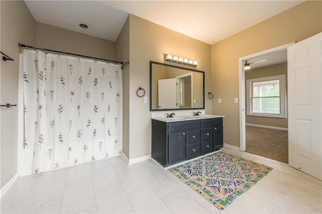 full bathroom with baseboards, curtained shower, double vanity, and a sink