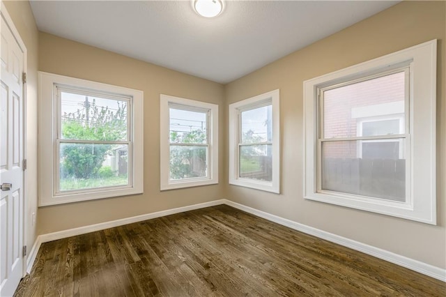 empty room featuring baseboards and dark wood-style flooring