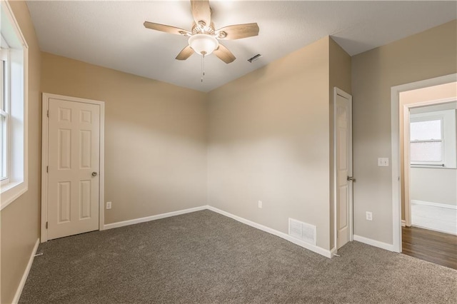 carpeted spare room with baseboards, visible vents, and a ceiling fan