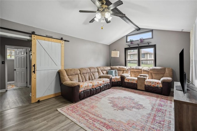 living area featuring a barn door, a ceiling fan, wood finished floors, vaulted ceiling with beams, and baseboards