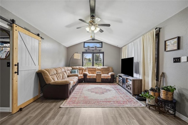 living room featuring a barn door, vaulted ceiling with beams, baseboards, a ceiling fan, and wood finished floors
