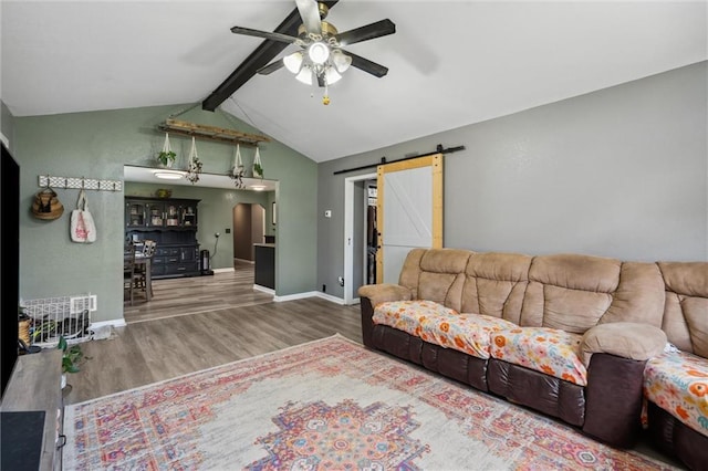 living room with a barn door, a ceiling fan, wood finished floors, lofted ceiling with beams, and arched walkways