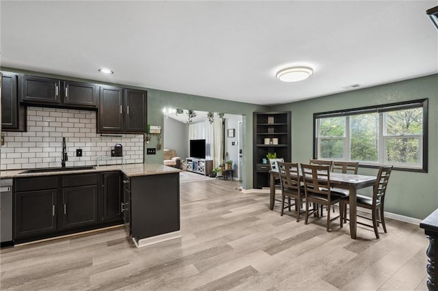 kitchen with light wood-style flooring, a sink, tasteful backsplash, baseboards, and visible vents