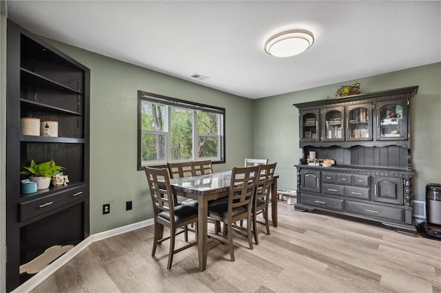 dining area featuring light wood-type flooring, visible vents, and baseboards